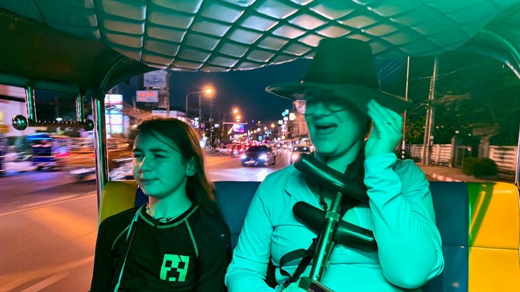 Son and mother ride side by side in a tuk tuk at night