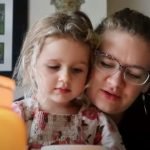 Mother and daughter read poetry by candlelight.