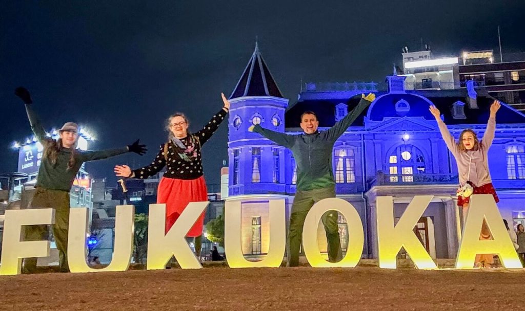 Family stands with the Fukuoka selfie sign in Tenjin Central Park