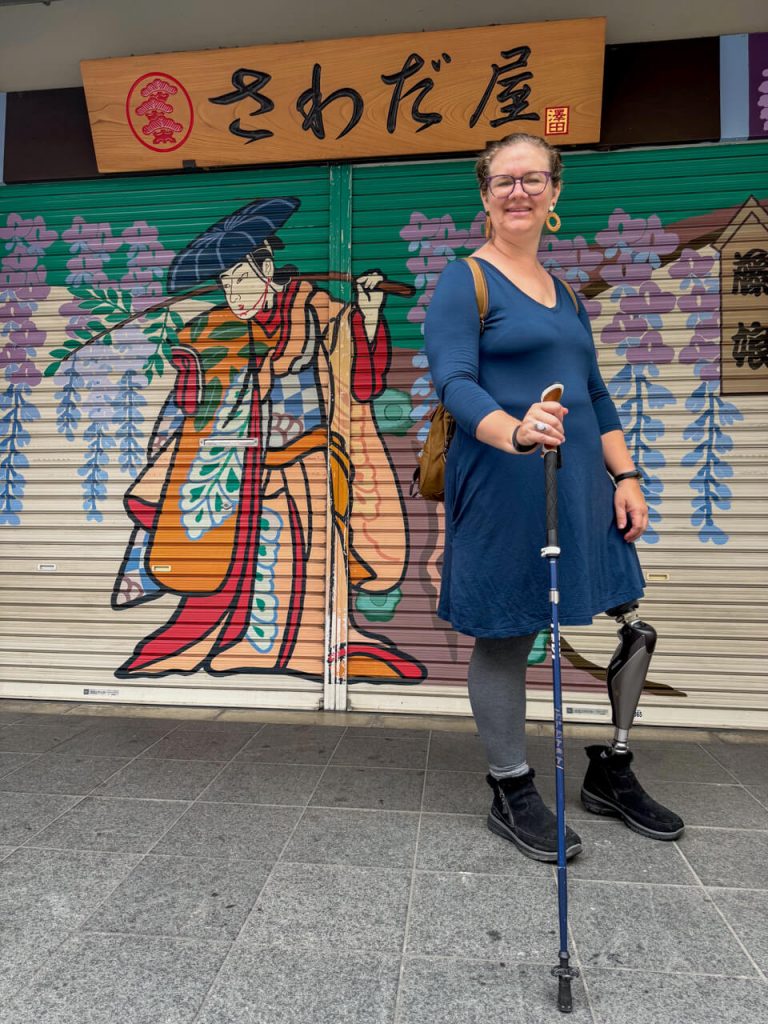 Woman with prosthetic leg standing next to samurai art in Tokyo