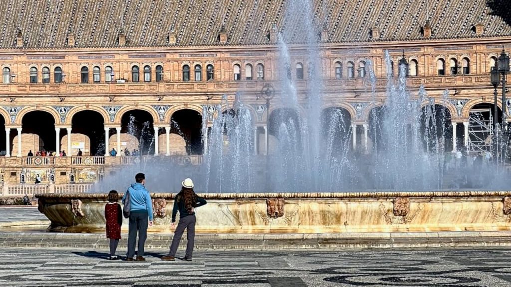 Father, son, and daughter admire a fountain in Sevilla, Spain